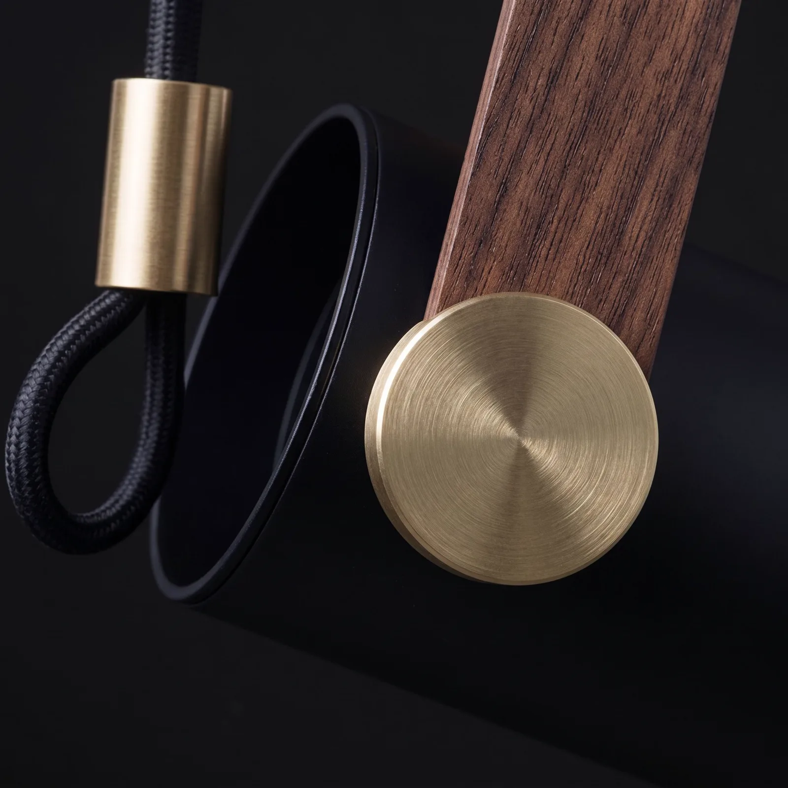 Macro of the brushed-brass pivot disc, the walnut-grain strap, and the matte-black body